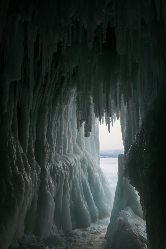 A frozen cave opening in deep winter, symbolizing shelter, waiting, and incubation in the dark season