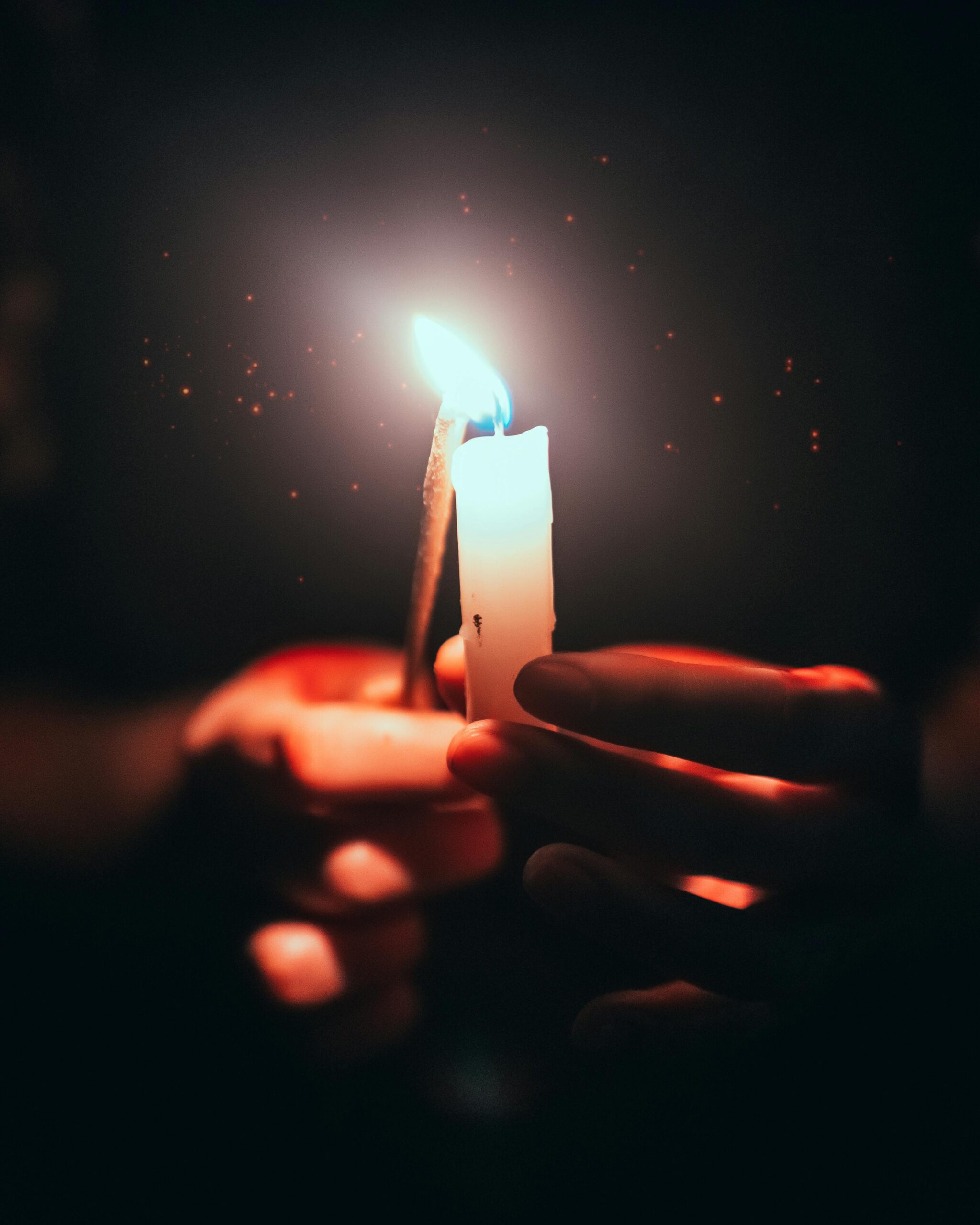 Lighting the Spark of Creativity Hands lighting a small candle flame in the dark symbolizing creative spark and inspiration