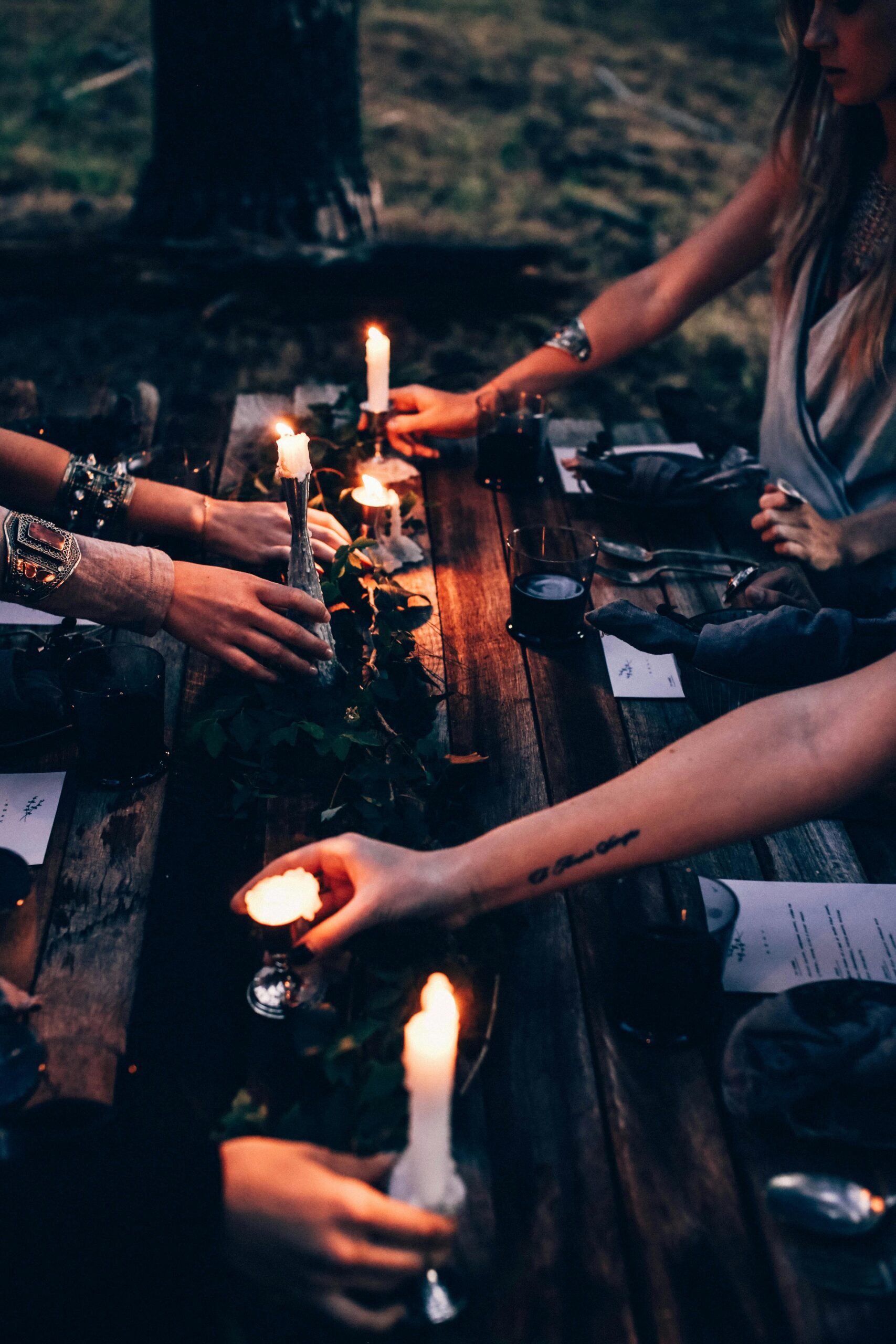 Candle ritual circle for creative renewal Women lighting candles around a wooden table during an intimate ritual gathering
