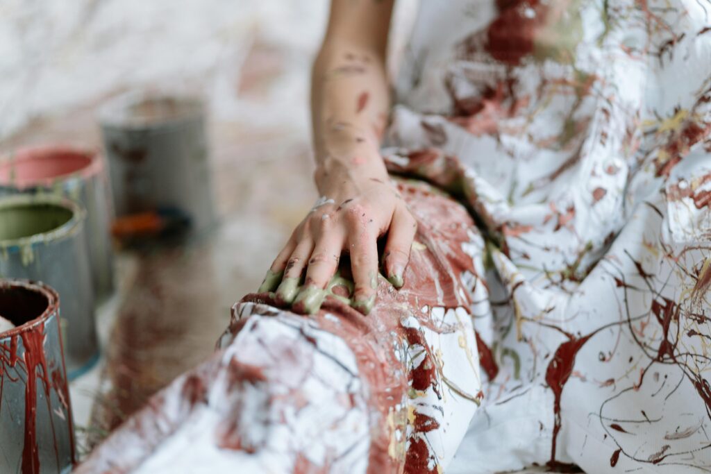 Artist with paint-covered hands and clothing embodying the creator archetype and creative energy