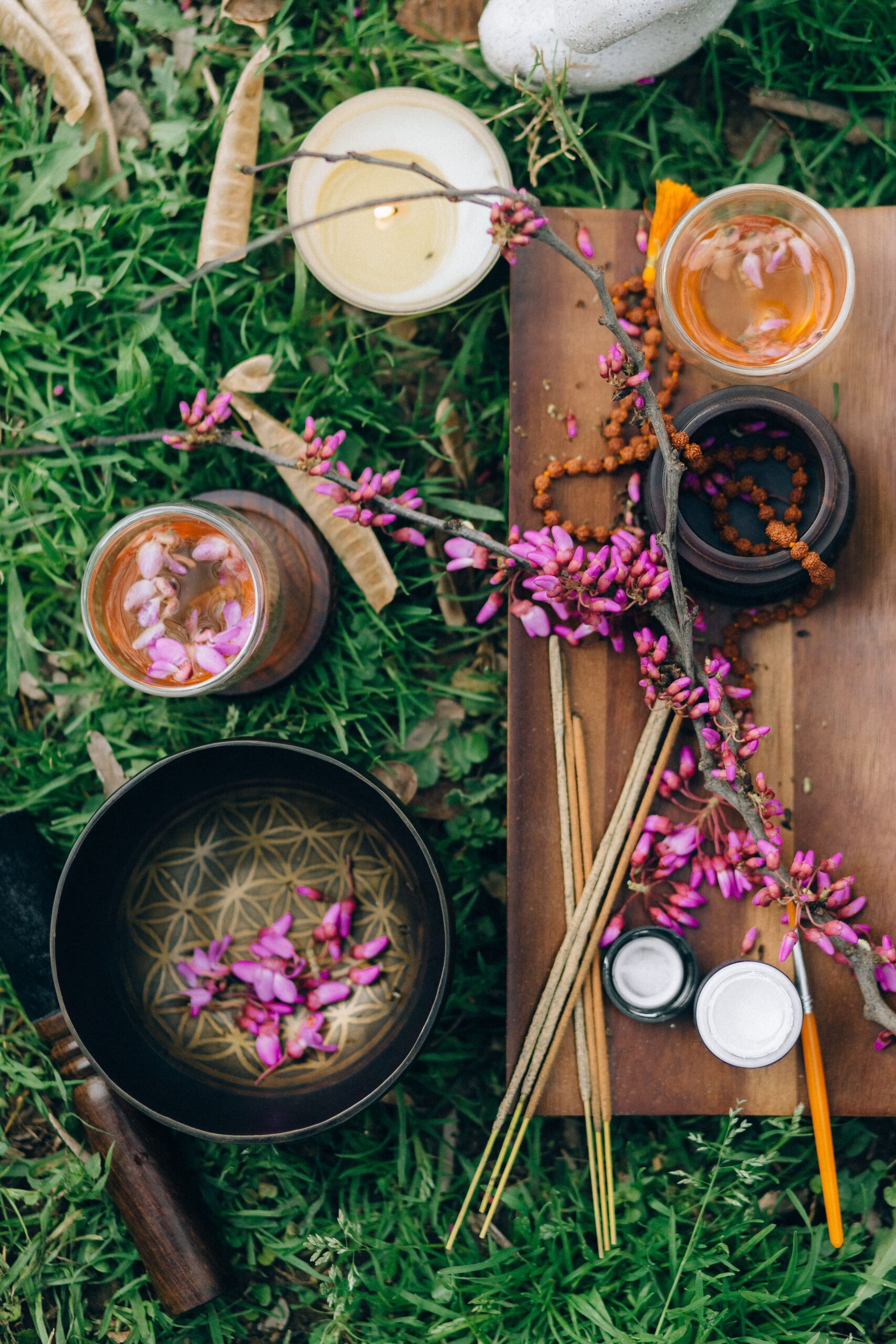 A Ritual in Nature Outdoor ritual space with candles, flowers, incense, tea, and a singing bowl arranged on the grass